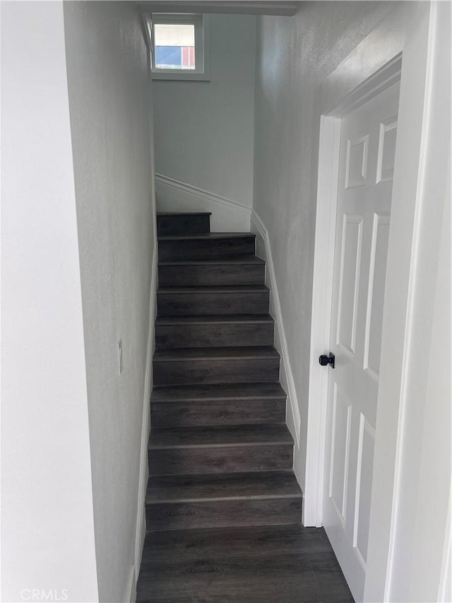 staircase featuring baseboards and wood finished floors