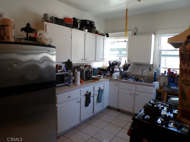 kitchen featuring light countertops, light tile patterned floors, white cabinets, stainless steel appliances, and a sink