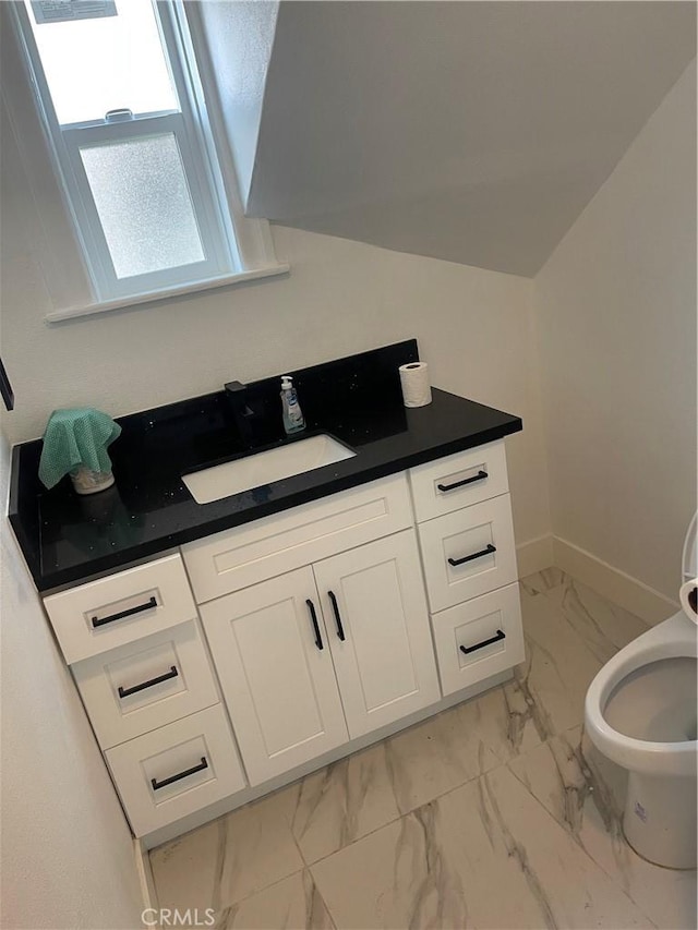 half bathroom featuring marble finish floor, toilet, vanity, and baseboards