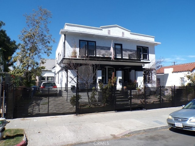 view of front facade with a fenced front yard, stucco siding, and a balcony