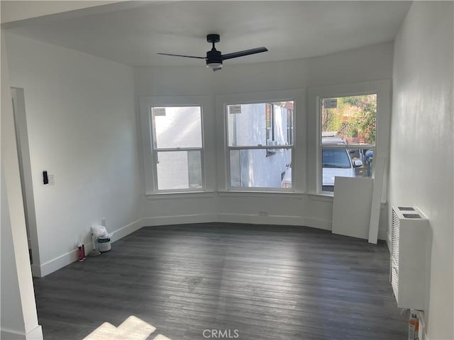 unfurnished room with baseboards, dark wood-type flooring, a ceiling fan, and radiator heating unit