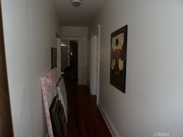 hall featuring baseboards and dark wood-type flooring