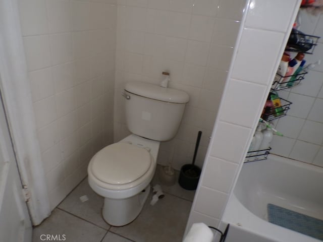 bathroom featuring toilet, tile walls, a bath, and tile patterned flooring