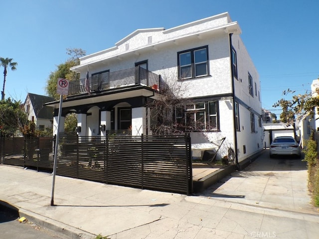 view of front of home featuring a fenced front yard, a balcony, and stucco siding