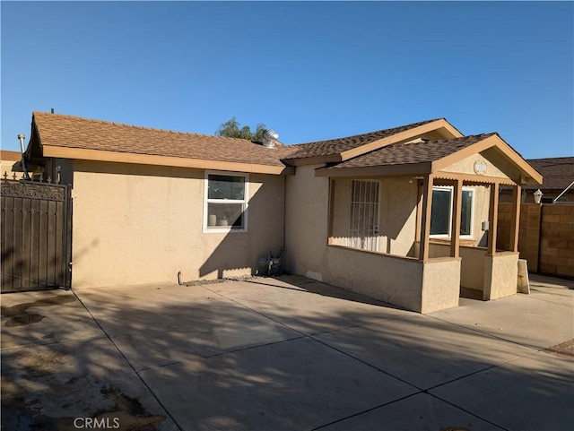 back of house featuring a gate, stucco siding, a patio area, and fence