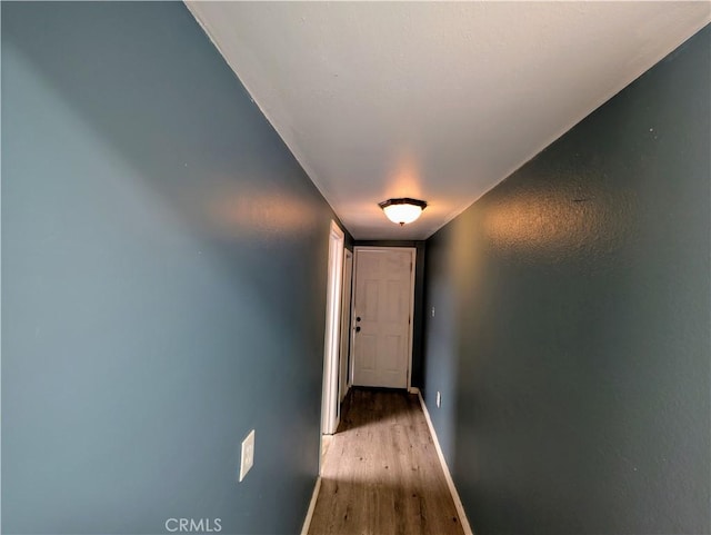 corridor with wood finished floors and baseboards