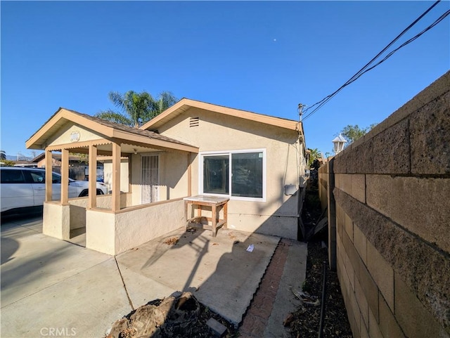 back of property with a patio area, stucco siding, and fence