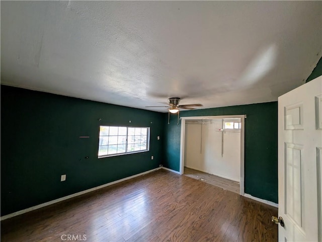 unfurnished bedroom with a closet, ceiling fan, baseboards, and wood finished floors