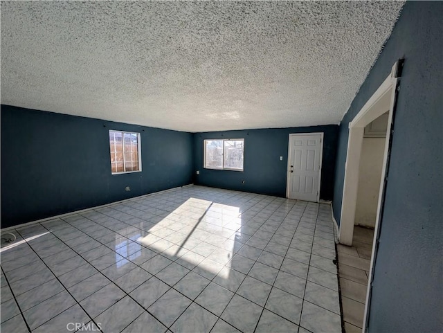 empty room featuring light tile patterned floors and a textured ceiling