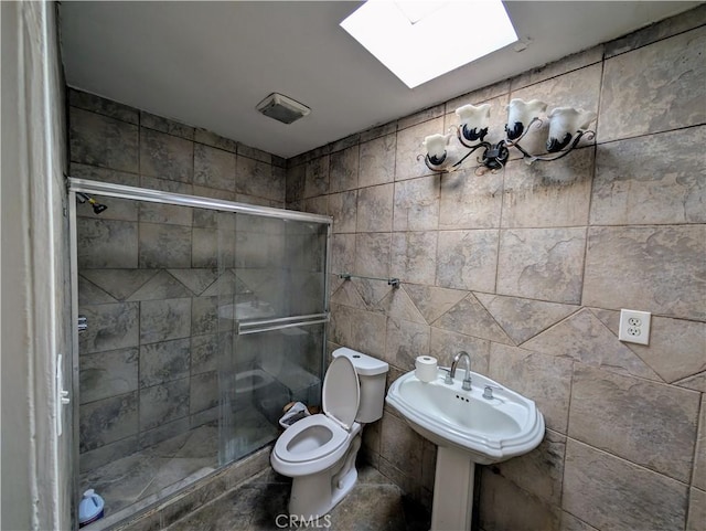 bathroom with a skylight, a stall shower, and toilet