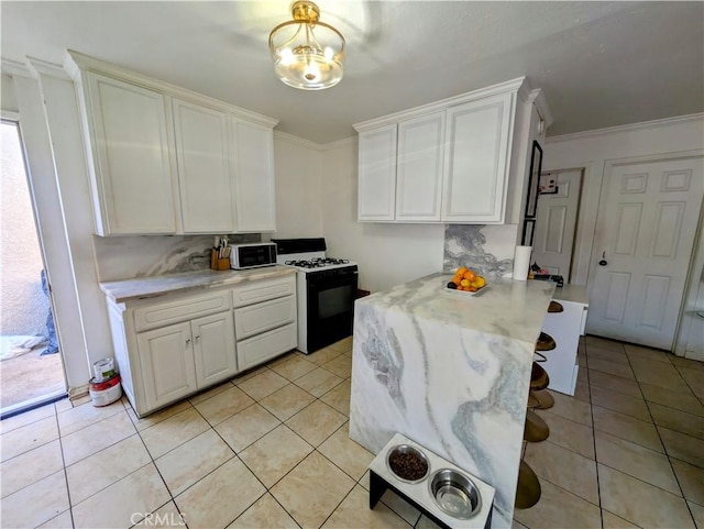 kitchen with light tile patterned flooring, white cabinets, gas stove, and crown molding