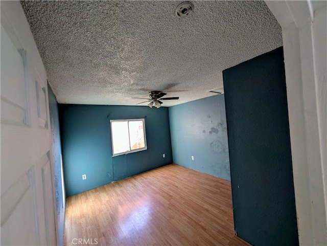 spare room featuring wood finished floors, a ceiling fan, and a textured ceiling