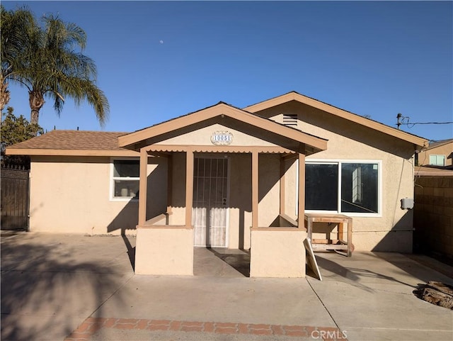 view of front of home featuring a patio area, fence, and stucco siding