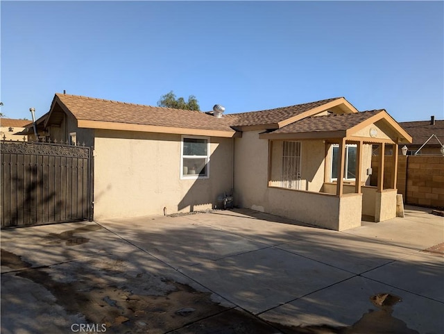 rear view of house featuring stucco siding, a patio area, and fence