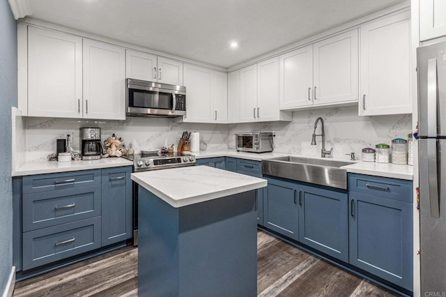 kitchen featuring dark wood-style floors, blue cabinetry, stainless steel appliances, and a sink