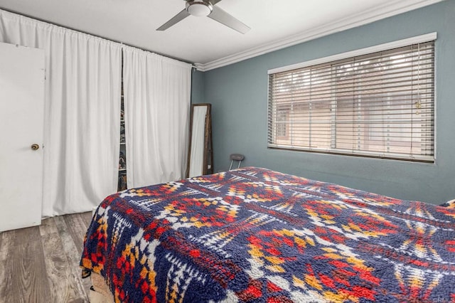 bedroom with a ceiling fan, crown molding, and wood finished floors