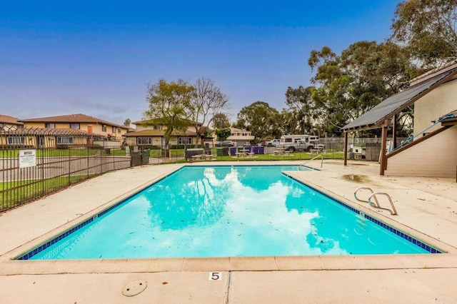 pool with a patio area, a residential view, and fence