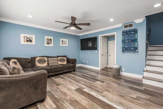 living area with stairway, ornamental molding, wood finished floors, and ceiling fan