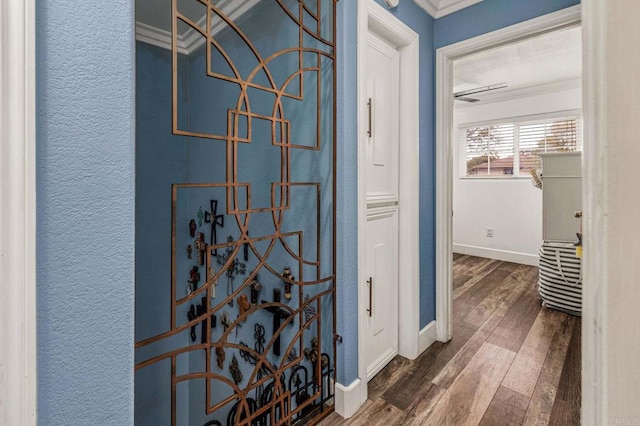 interior space with baseboards, wood finished floors, crown molding, and a textured wall