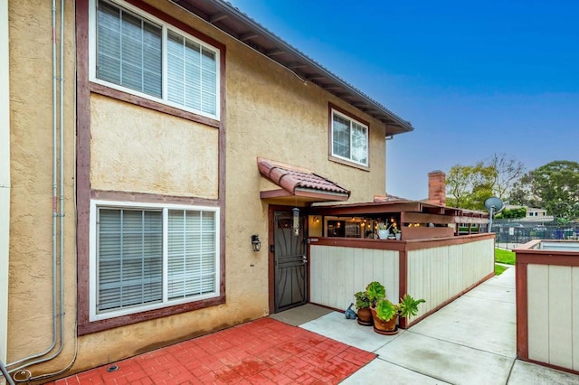 entrance to property featuring a patio, fence, and stucco siding