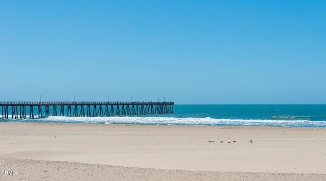 property view of water featuring a pier and a beach view