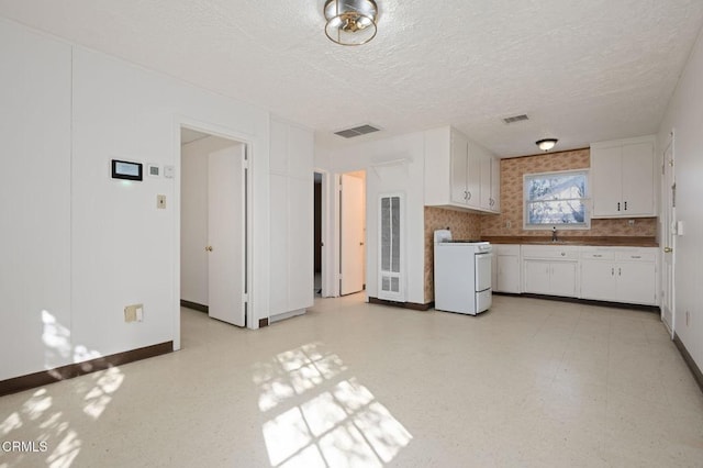 kitchen featuring stove, white cabinets, light floors, and visible vents