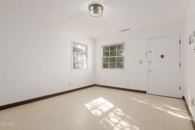 foyer with visible vents, a textured ceiling, and baseboards