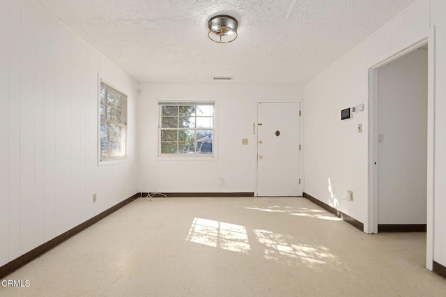 foyer entrance with tile patterned floors, a textured ceiling, and baseboards