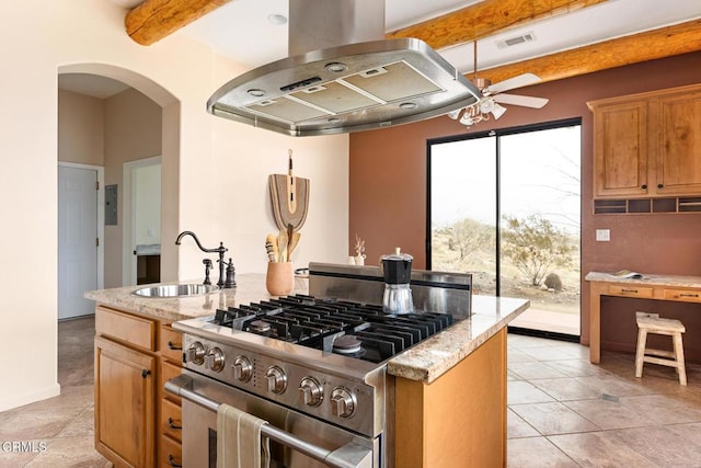 kitchen featuring a ceiling fan, island exhaust hood, a sink, gas stove, and arched walkways