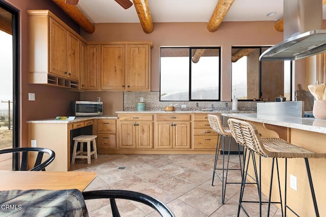 kitchen featuring beam ceiling, island exhaust hood, stainless steel microwave, tasteful backsplash, and ceiling fan