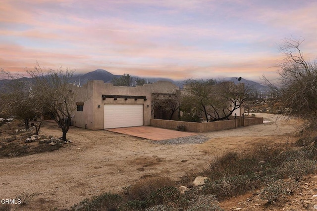 view of front of property featuring a mountain view, stucco siding, an attached garage, and concrete driveway