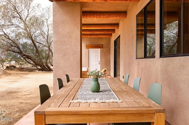 exterior space featuring beamed ceiling and a textured wall