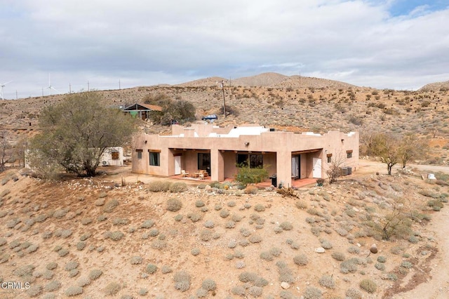 rear view of house with a patio area, stucco siding, and a mountain view