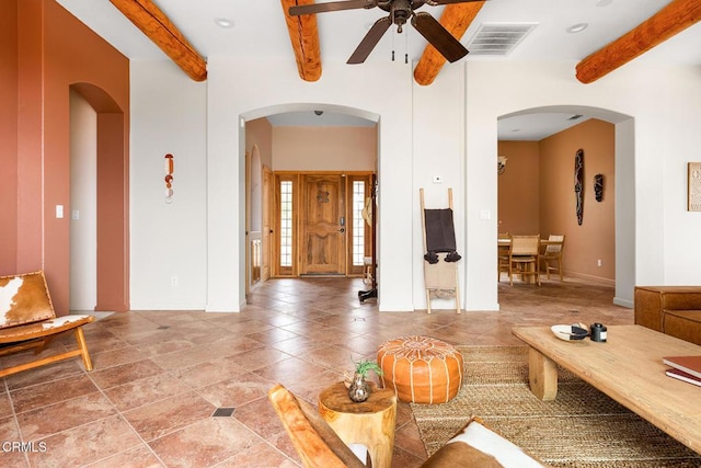 unfurnished living room featuring arched walkways, visible vents, beamed ceiling, and ceiling fan