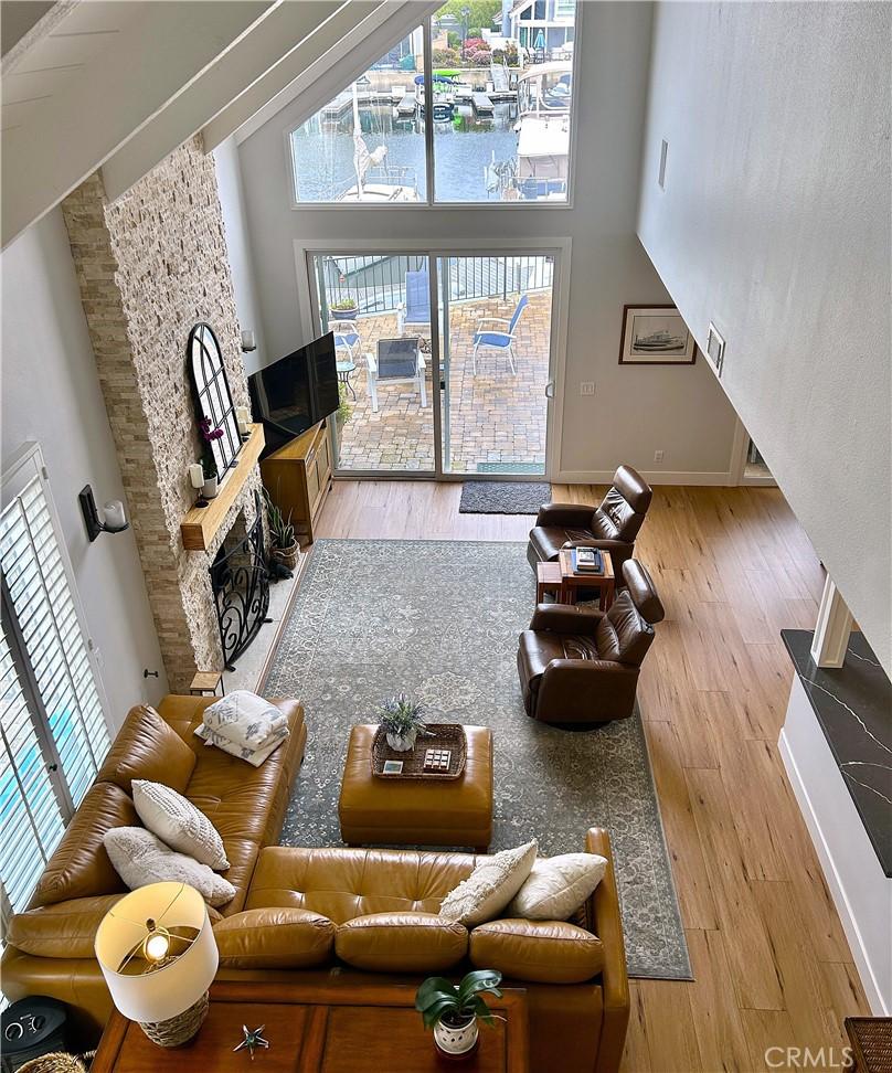 living area featuring wood finished floors, a fireplace, baseboards, and a towering ceiling