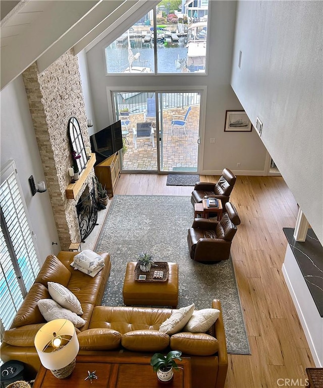 living area featuring wood finished floors, a fireplace, baseboards, and a towering ceiling