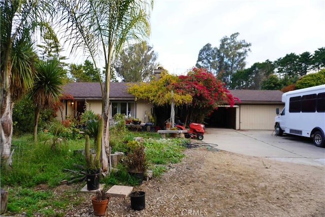 view of front facade with an attached garage, driveway, and a chimney