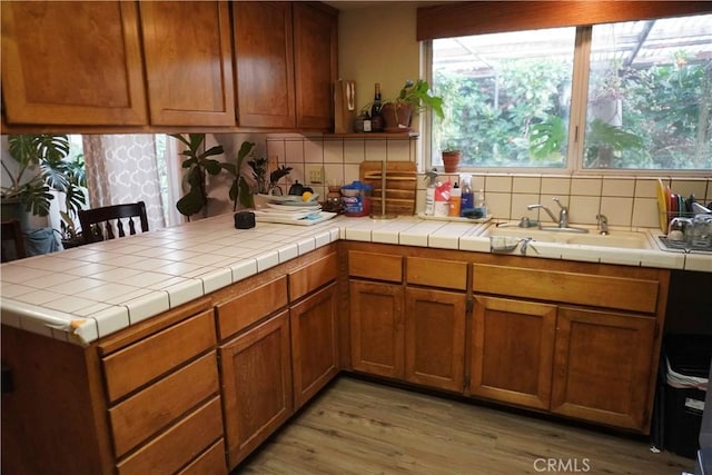 kitchen featuring a sink, tasteful backsplash, a peninsula, and light wood finished floors