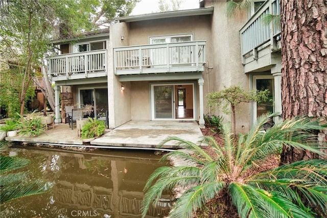 rear view of house with stucco siding and a patio