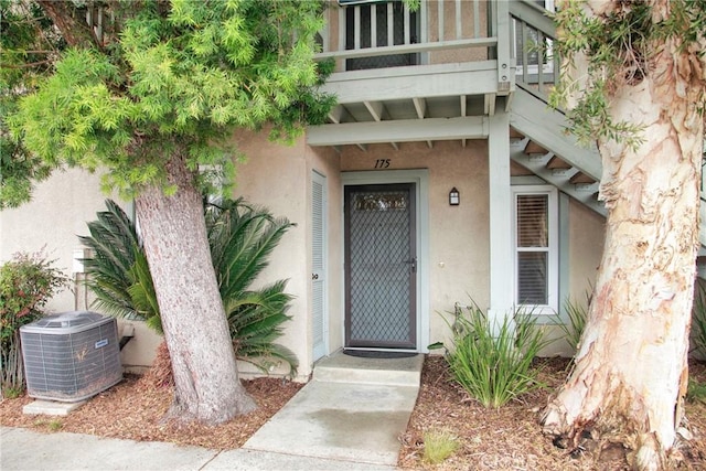 property entrance with cooling unit and stucco siding