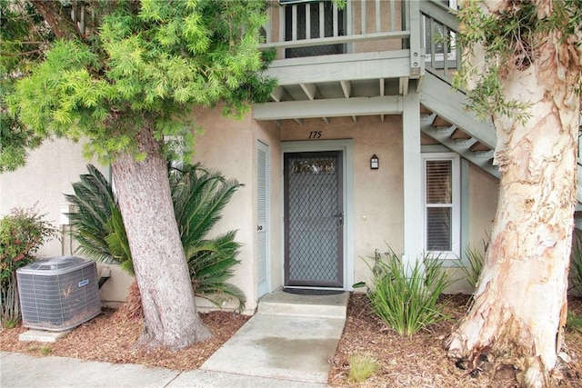 property entrance featuring cooling unit and stucco siding
