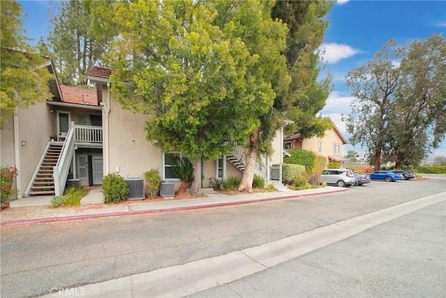 view of front of home featuring stairway, stucco siding, and cooling unit