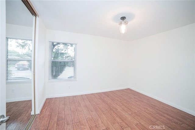 spare room featuring baseboards and wood finished floors