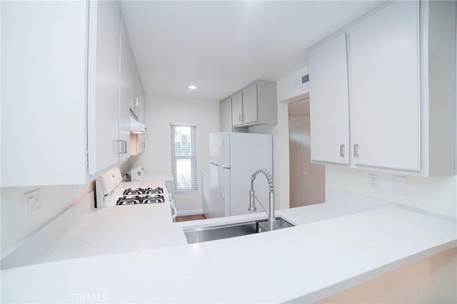 kitchen with a sink, white appliances, under cabinet range hood, and light countertops