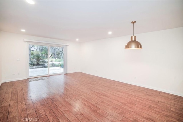empty room with light wood finished floors, recessed lighting, and baseboards