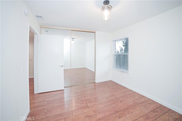 unfurnished room with visible vents, baseboards, and wood finished floors