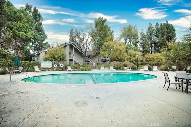 community pool with a patio area and fence