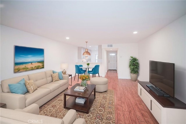 living area featuring recessed lighting, light wood-style floors, and visible vents