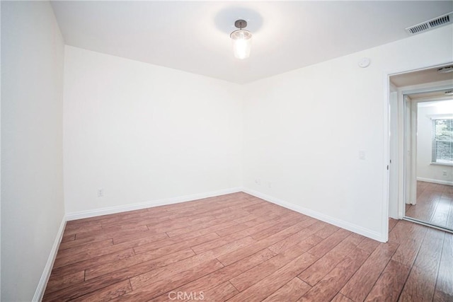 unfurnished room with wood finished floors, visible vents, and baseboards