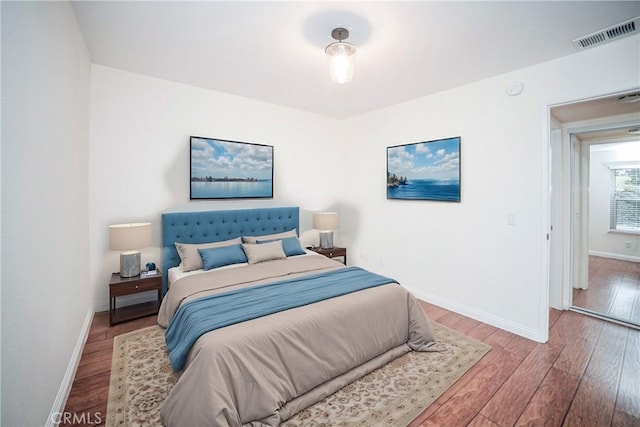 bedroom with visible vents, baseboards, and wood finished floors